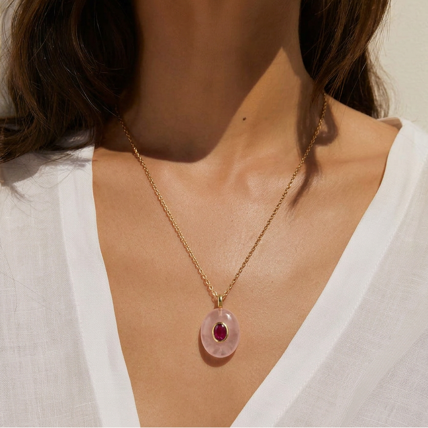 Descubre el Colgante Óvalo de Cuarzo Rosa de Bendita Eva con circonita color rubí. Elaborado en piedra natural y acero inoxidable 316L bañado en oro de 18K. Waterproof e inspirado en el amor, la armonía y los vínculos que dan sentido a la vida.