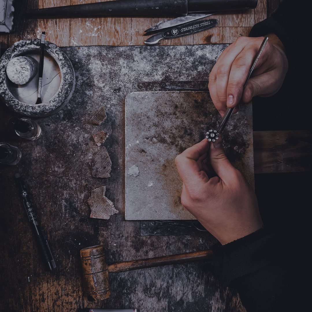 Manos de una artesana elaborando una joya de forma manual en un taller - Bendita Eva