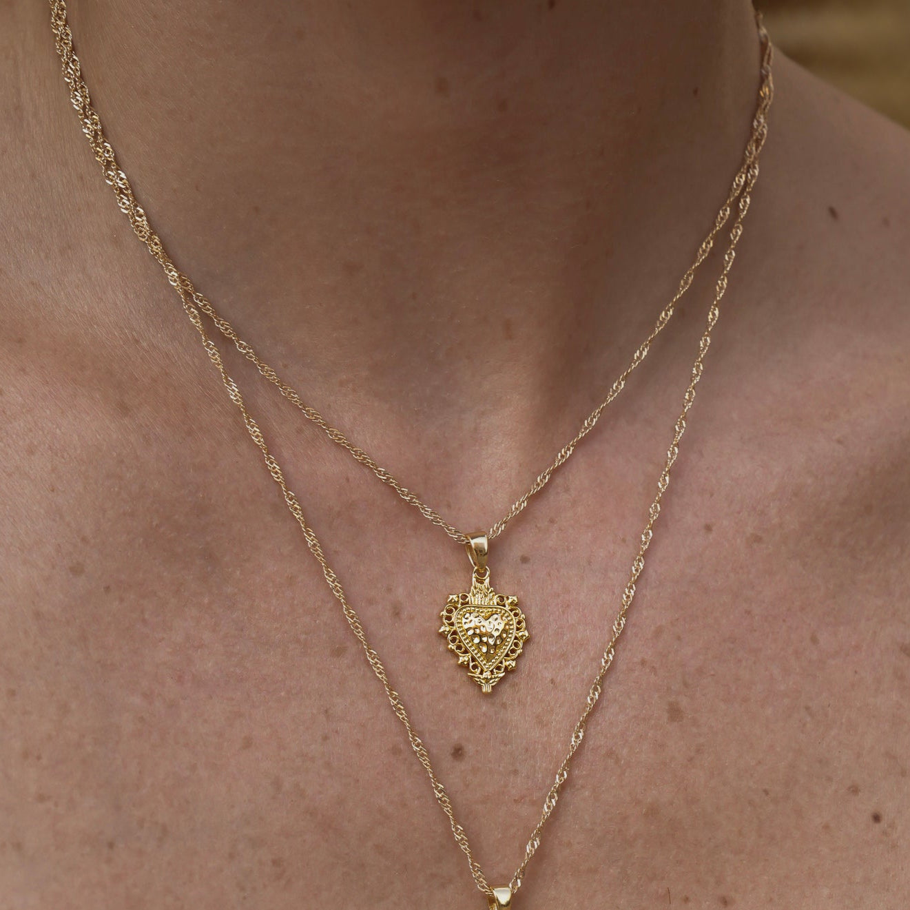 Cadena Singapur de Bendita Eva en plata de ley 925 lucida en modelo en layering con colgante Sagrado Corazón. Ajustable 45-50 cm, versátil y brillante, ideal para crear looks personalizados.