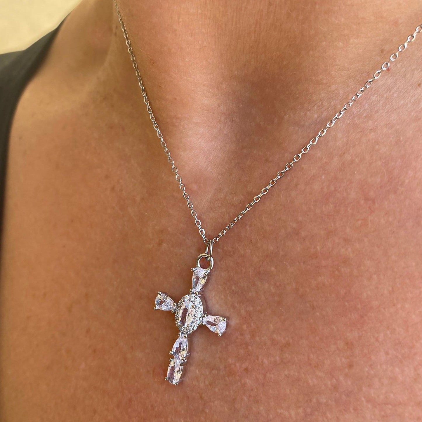 Colgante Cruz de circonitas blancas de plata de ley 925 con baño de rodio lucido en modelo, vista lateral en cuello, mostrando diseño artesanal y elegancia - Bendita Eva
