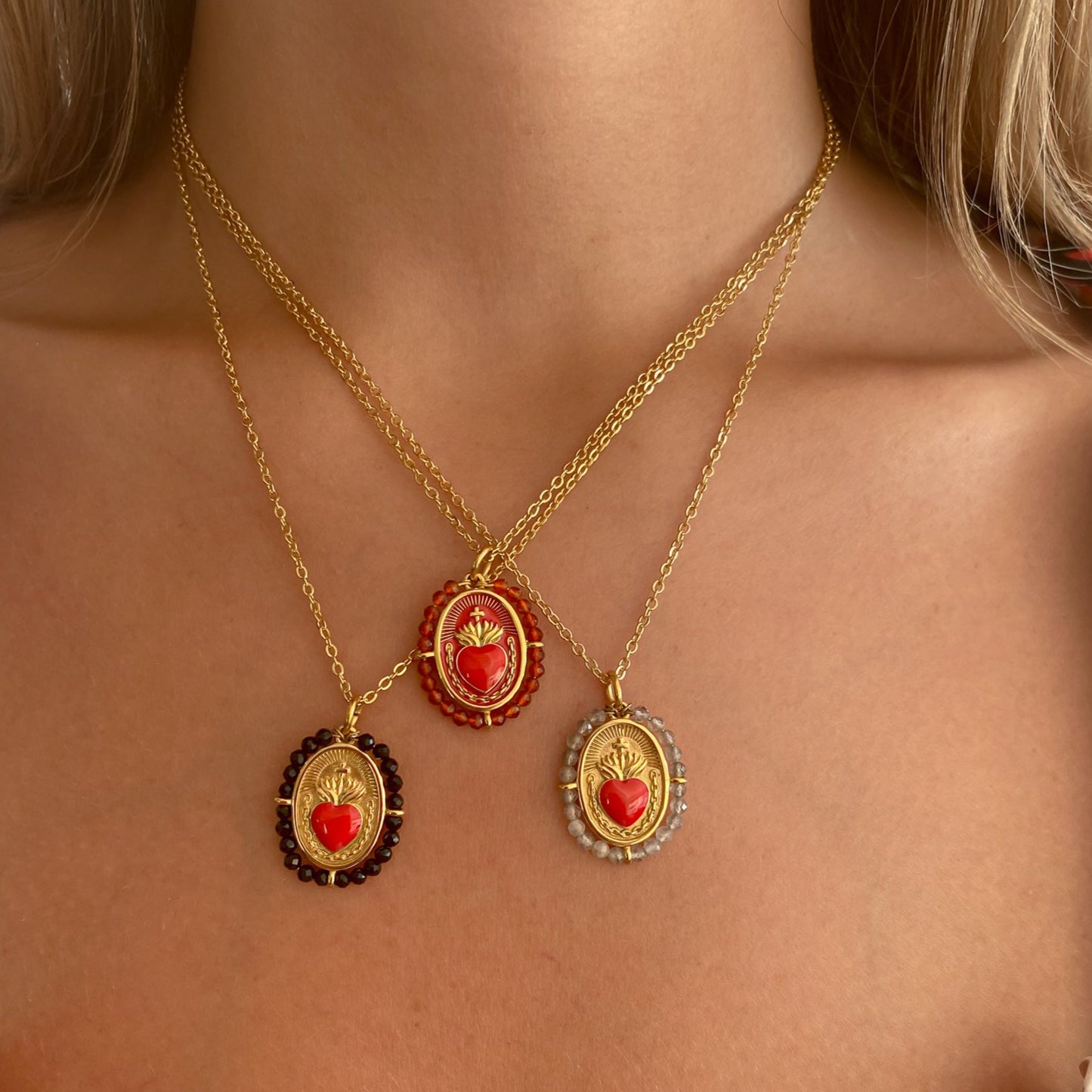 Colgante Sagrado Corazón Coral de Bendita Eva lucido en modelo en layering con otros tres colgantes, mostrando diseño artesanal y piedras de coral rojo protector.

