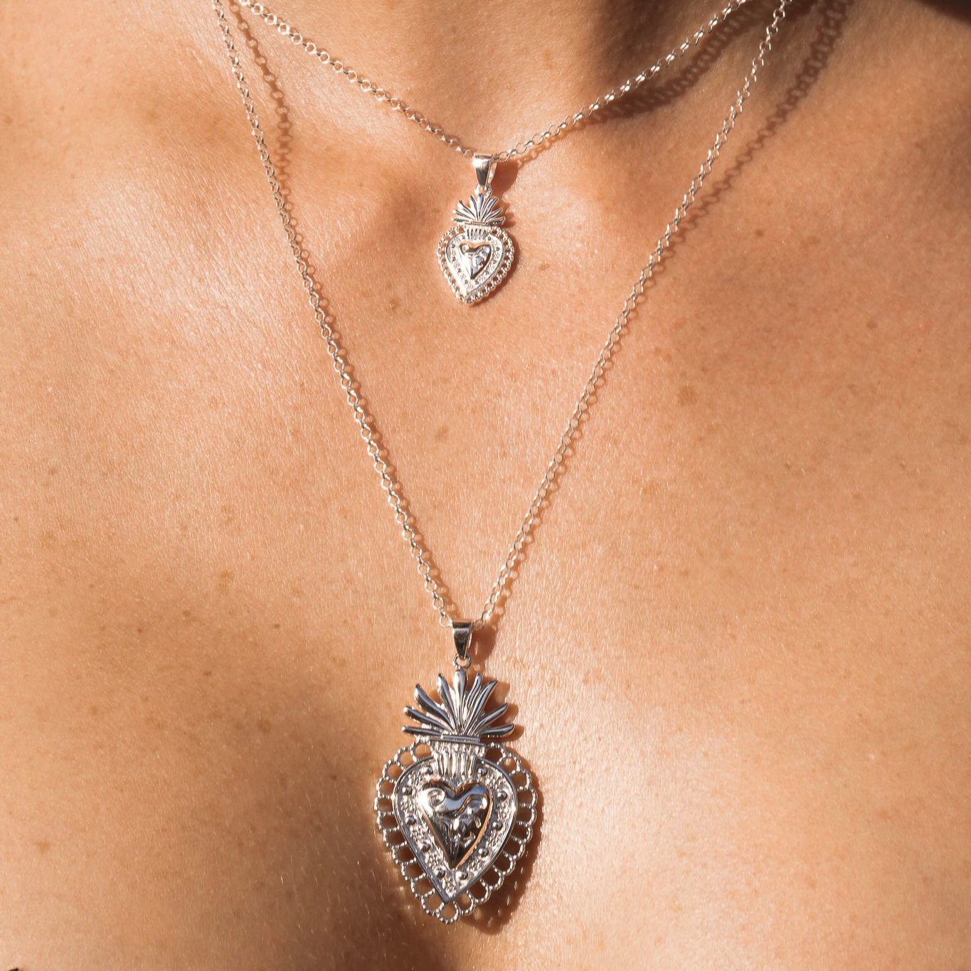 Modelo luciendo colgante Sagrado Corazón de Bendita Eva en plata de ley, combinado en layering con otros colgantes de la colección BENDITA.
