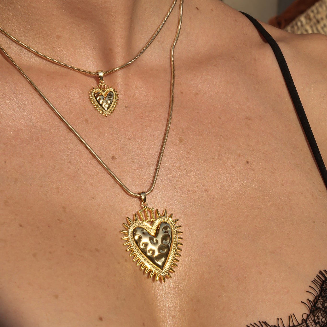 Modelo luciendo colgante Sagrado Corazón Protection de Bendita Eva en oro, combinado en layering con otros colgantes de la colección BENDITA.