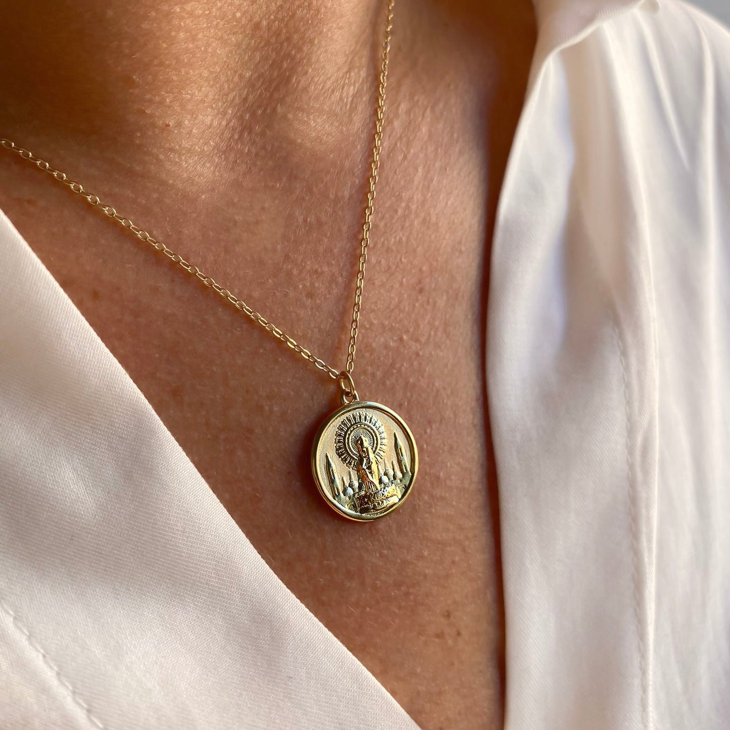 Medalla de la Virgen del Pilar en plata de ley 925 bañada en oro de 18K lucida como colgante por una modelo de Bendita Eva.