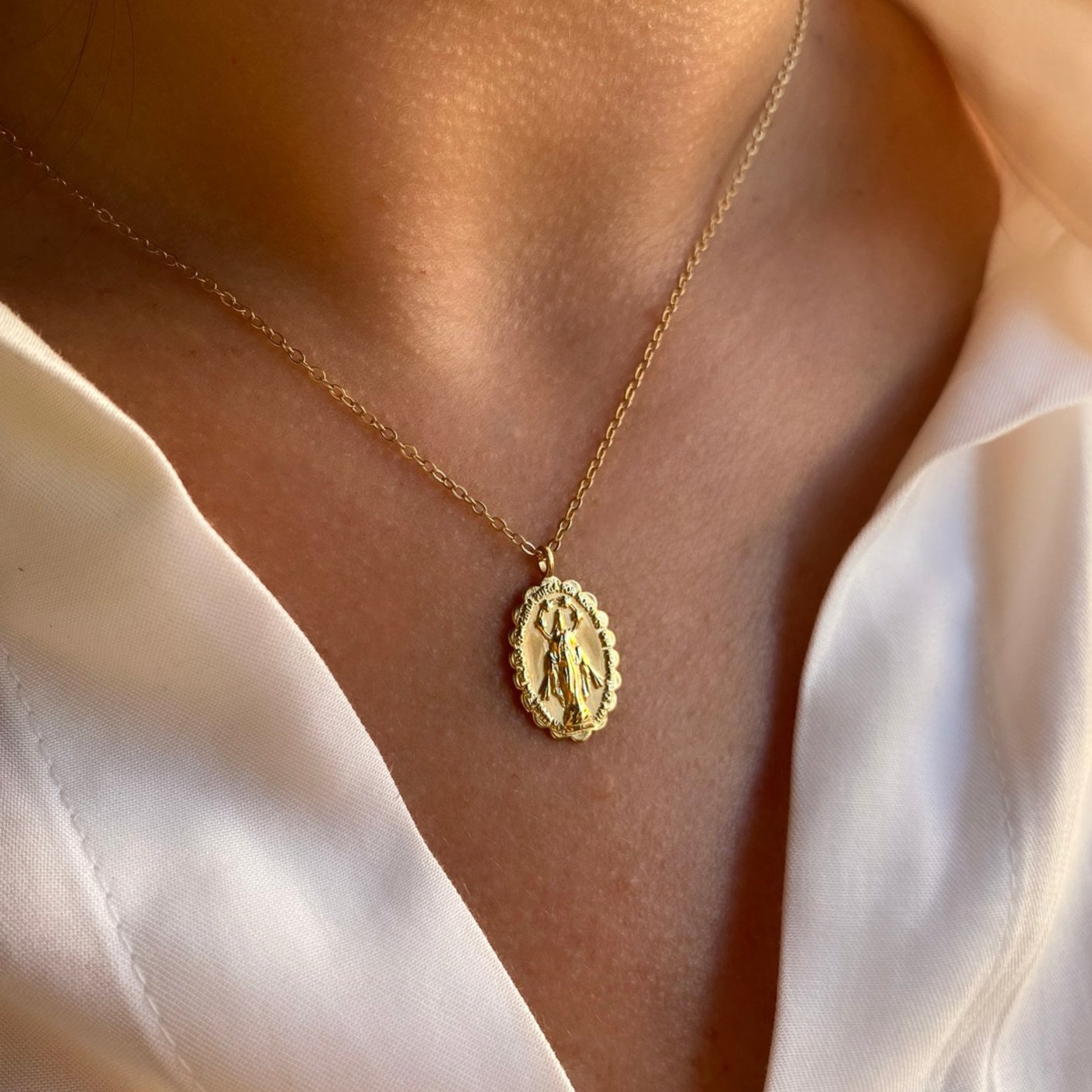 Medalla de la Virgen de la Milagrosa en plata de ley 925 bañada en oro de 18K lucida como colgante por una modelo de Bendita Eva.