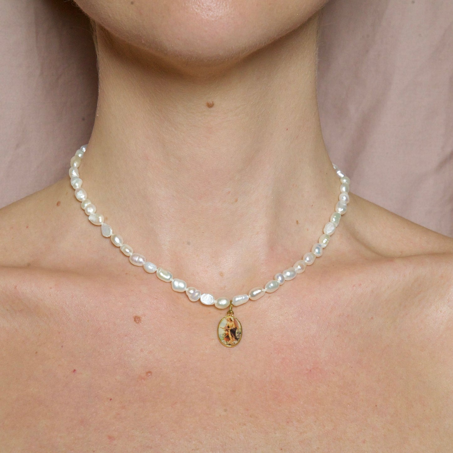 Medalla con un ángel y sus 40 cm compuesto de perlas barrocas naturales de 5 mm hacen de este colgante una joya especial y única. Ángel Pearl  es una medalla formada por perlas naturales.