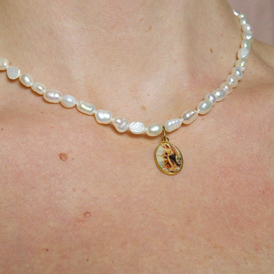 Medalla con un ángel y sus 40 cm compuesto de perlas barrocas naturales de 5 mm hacen de este colgante una joya especial y única. Ángel Pearl es una medalla formada por perlas naturales.